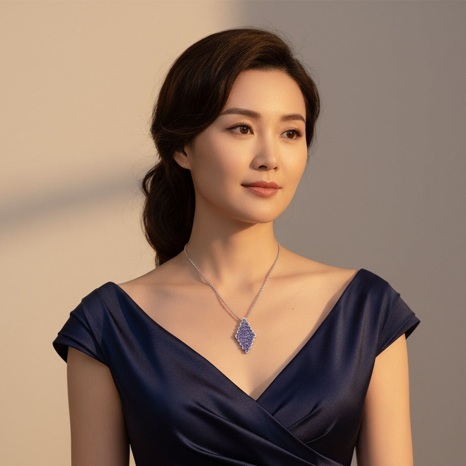 Woman wearing a dark blue dress with a necklace against a neutral background