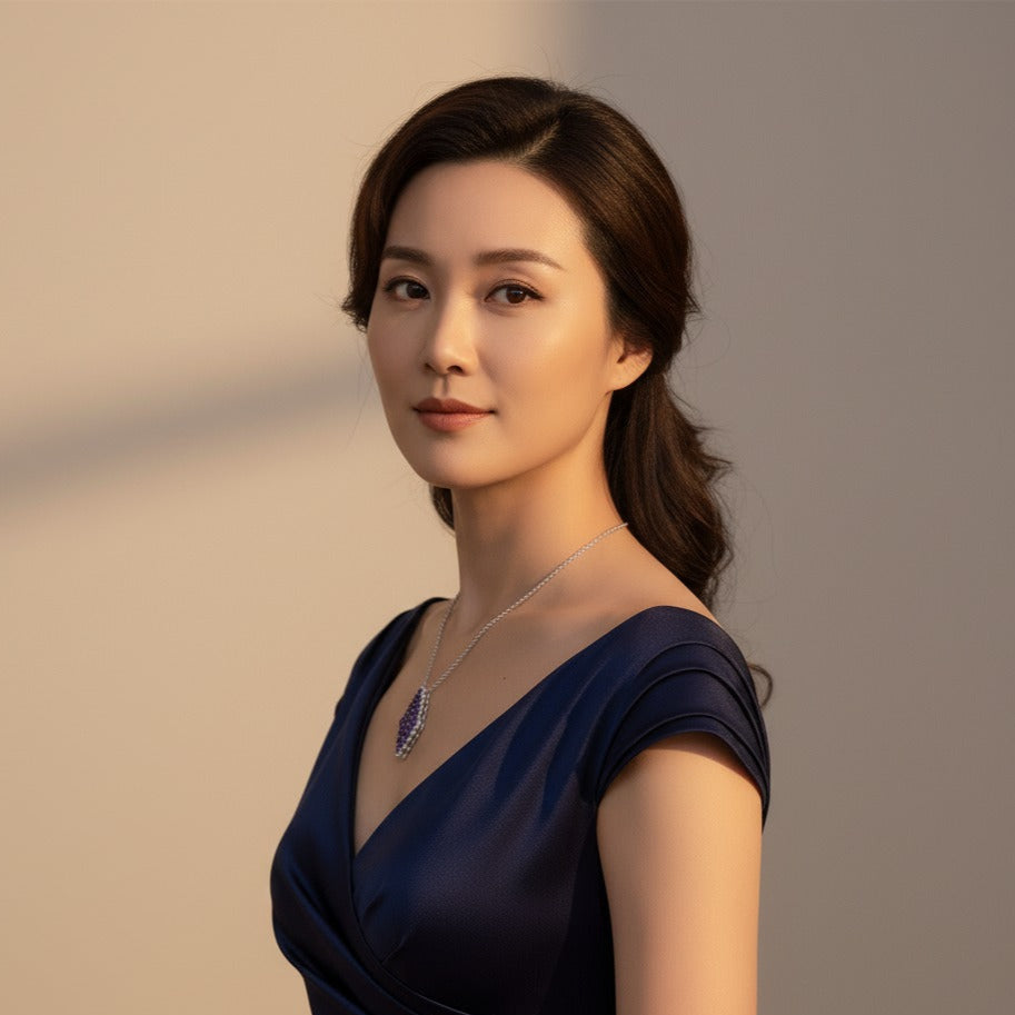 Woman wearing a dark blue dress with a necklace against a neutral background