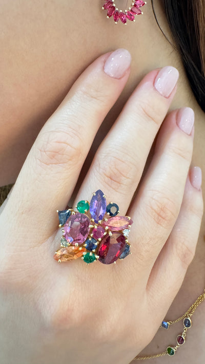 Multicolored gemstone ring on a hand with matching earrings.