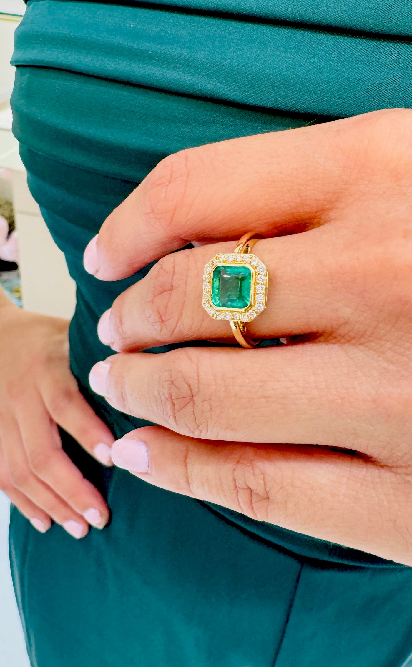 Emerald & Diamond in 18K Yellow Gold - Tresor Collection Gold emerald ring on hand – square-cut gemstone with halo diamonds shown in natural lighting