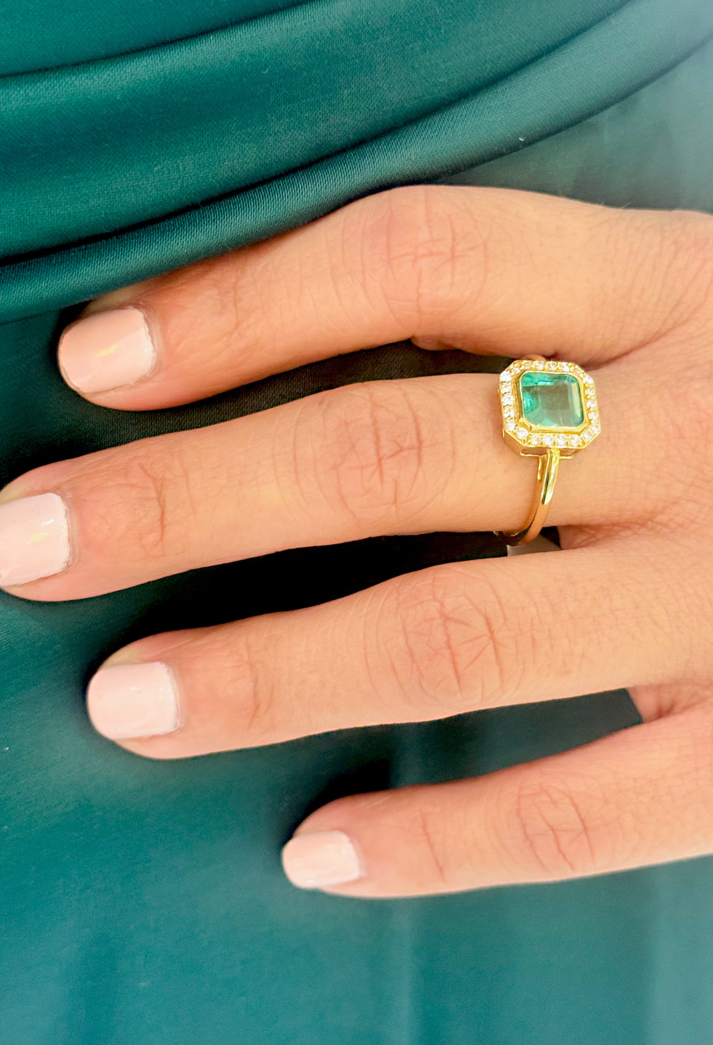 Emerald & Diamond in 18K Yellow Gold - Tresor Collection Lifestyle shot of emerald halo ring – gold band and radiant green gemstone accentuating outfit