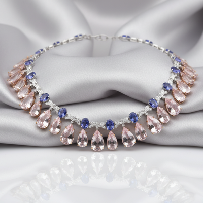 Necklace with pink teardrop-shaped stones and blue accents on a gray fabric background