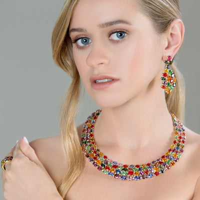 Woman wearing a colorful necklace and earrings against a gray background