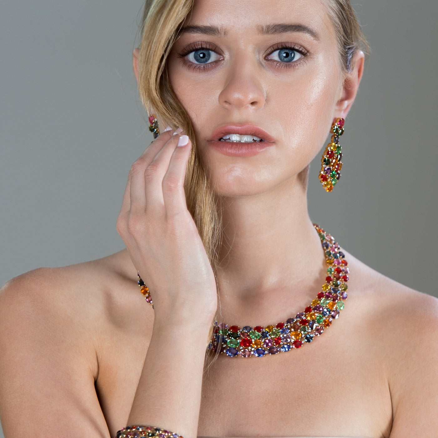 Woman wearing a colorful necklace and earrings against a gray background