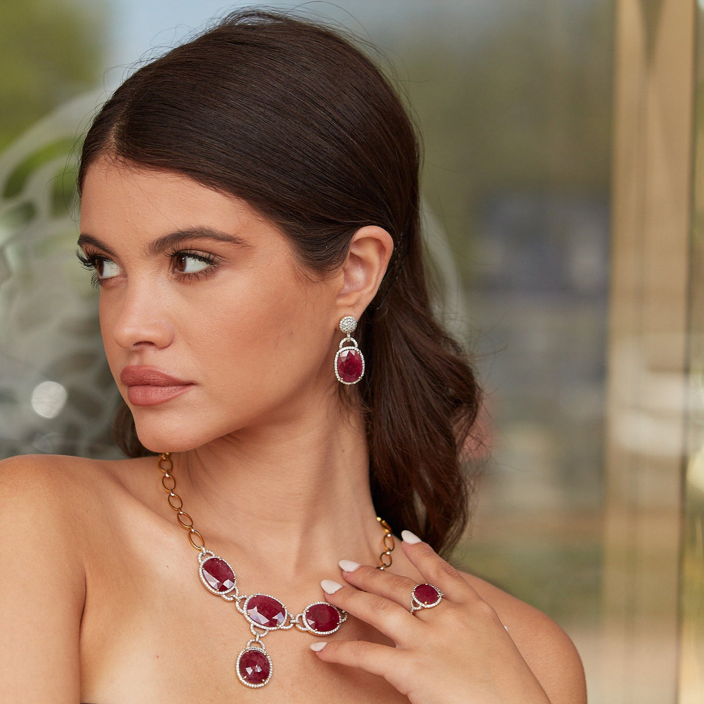 Close-up side view of model wearing ruby and diamond drop earrings in 18k yellow gold – Tresor Collection Miami jewelry.