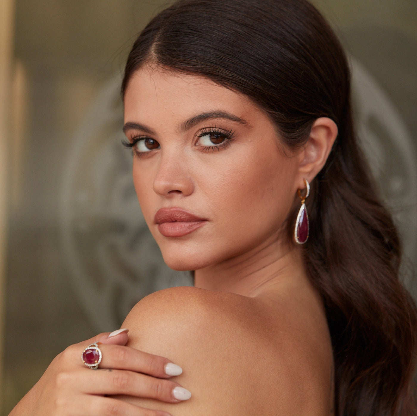 Angled view of model wearing ruby and diamond teardrop earrings in 18k yellow gold – Tresor Collection jewelry