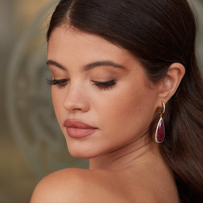 Close-up of model wearing ruby and diamond teardrop earrings in 18k yellow gold – Tresor Collection luxury jewelry USA. Handcrafted 18K gold ruby earrings styled for festive elegance – fine jewelry boutique design