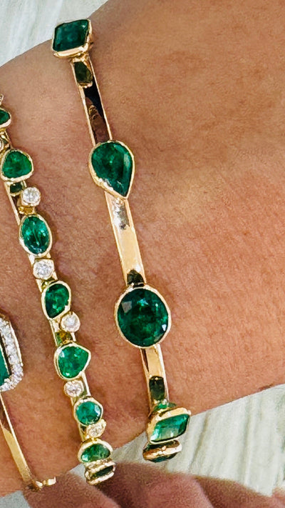 Emerald Mix Shape Bangle In 18K Yellow Gold - Tresor Collection Gold emerald bangle worn on wrist – capturing the bracelet’s elegance and colorful emerald stones.