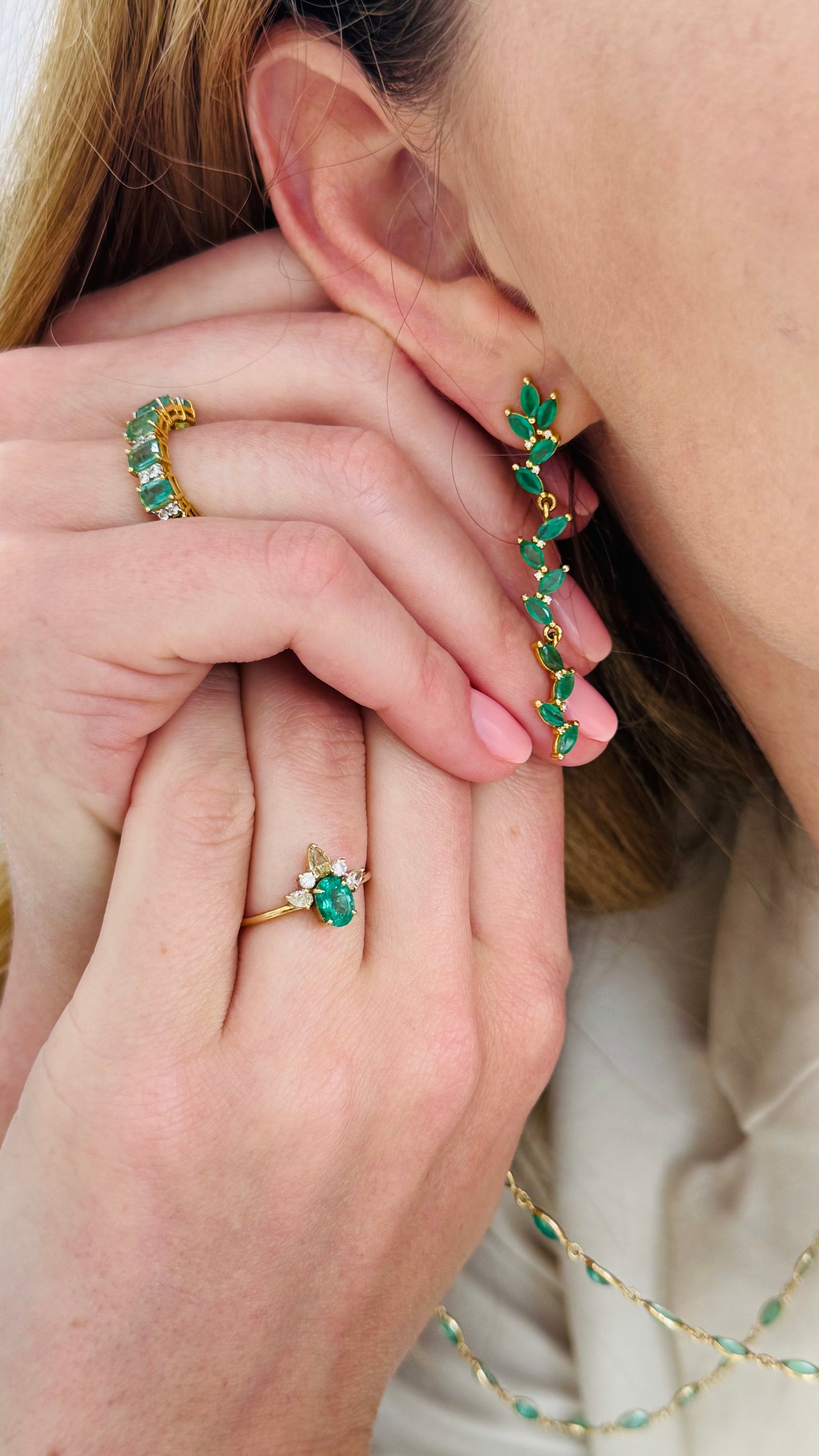 Close-up of emerald green earrings and ring on a person's hand Close-up of model holding emerald leaf earrings – luxury fine jewelry detailing