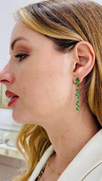 Close-up of a woman wearing green emerald earrings with a blurred background Front view of model wearing emerald leaf earrings – premium statement jewelry