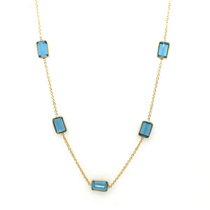 Necklace with blue gemstones on a white background Blue Topaz station necklace flatlay – elegant handcrafted fine jewelry by Tresor Collection