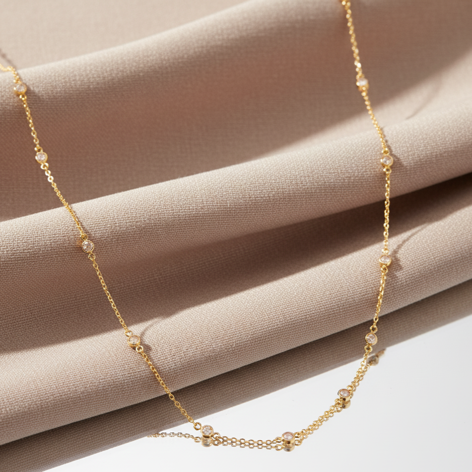 Gold necklace with small beads on a beige fabric background