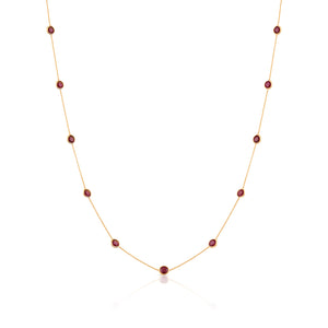 A round necklace made of 18k yellow gold with a series of red gemstones attached to it. 18K gold multi-gemstone necklace flatlay – luxury fine jewelry by Tresor Collection