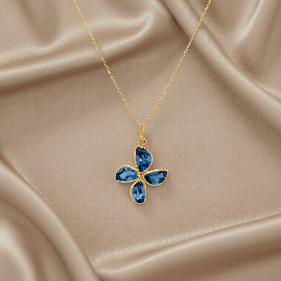 Gold necklace with a blue butterfly pendant on a beige fabric background London Blue Topaz flower pendant displayed on silk fabric – premium handcrafted jewelry