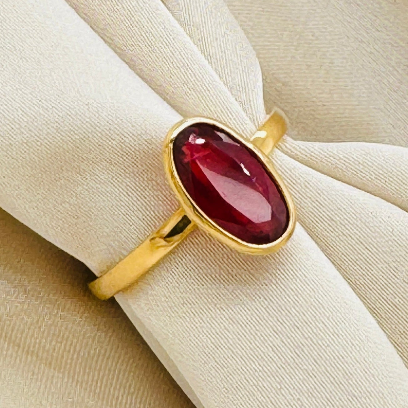 Close-up of oval orange sapphire ring on beige fabric – luxury gold gemstone ring by Tresor Collection