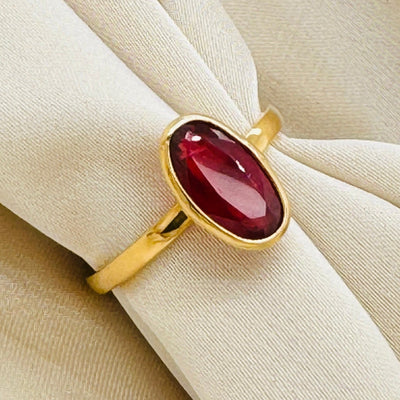 Close-up of oval orange sapphire ring on beige fabric – luxury gold gemstone ring by Tresor Collection