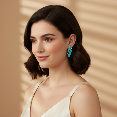 Woman wearing a white dress and turquoise earrings against a beige background