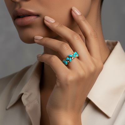 Close-up of a hand wearing a turquoise ring with a neutral background