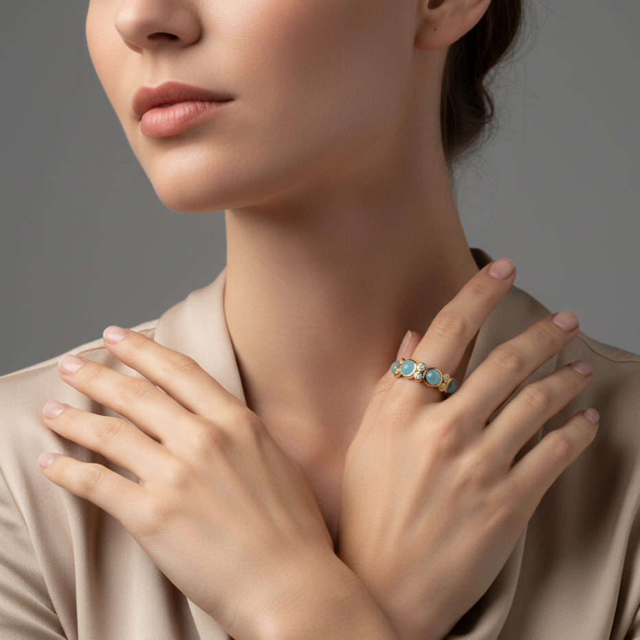 Close-up of a woman wearing a gold ring with blue gemstones on a neutral background