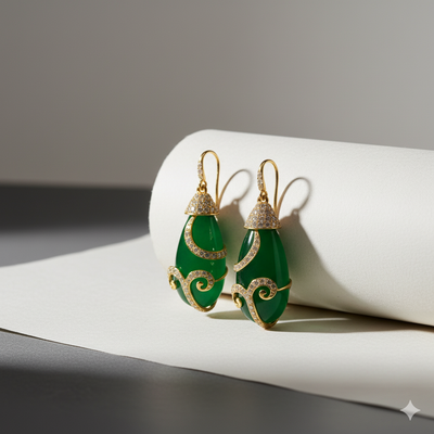 Green teardrop earrings with gold and diamond accents on a white surface.