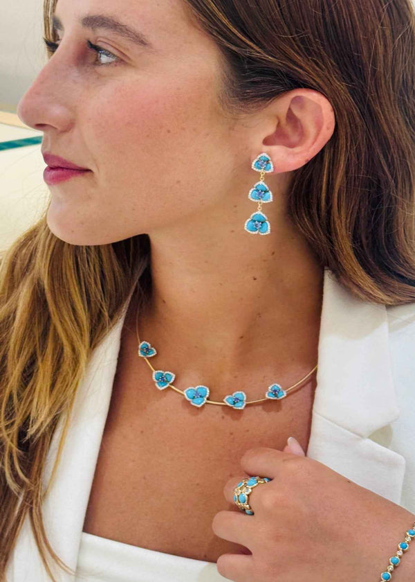 Woman wearing turquoise heart-shaped jewelry including earrings, necklace, ring, and bracelet.