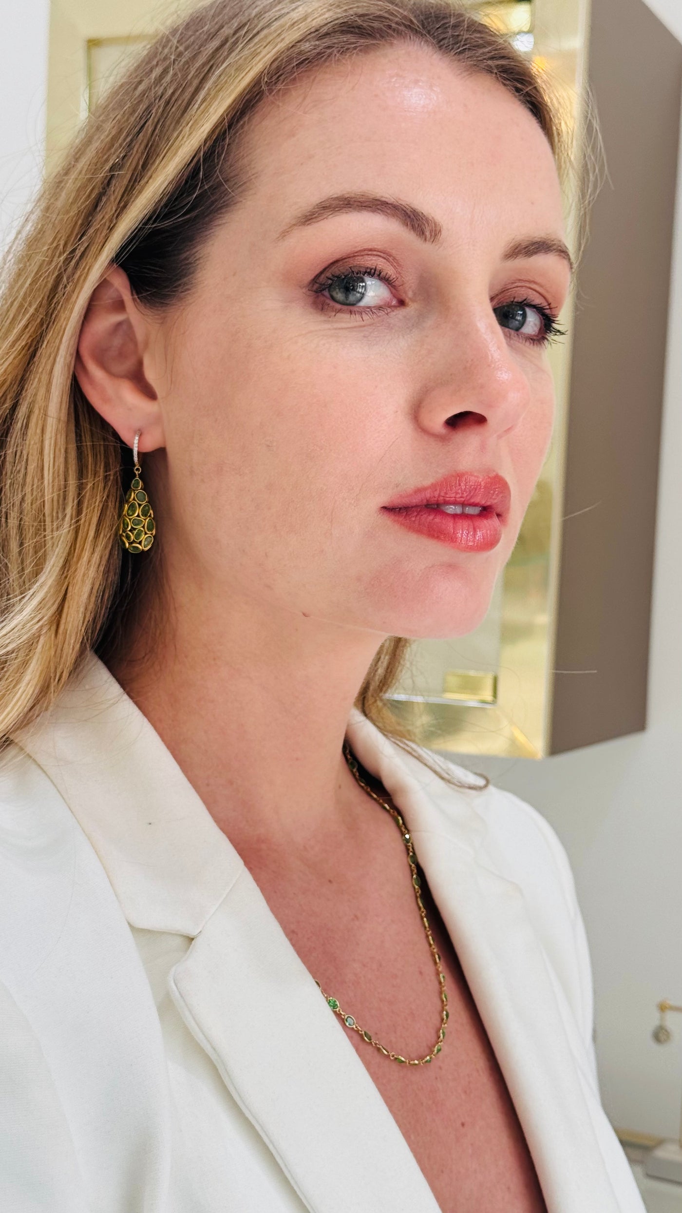 Woman wearing gold earrings and necklace, close-up of face Model portrait wearing green gemstone drop earrings – elegant fine jewelry look