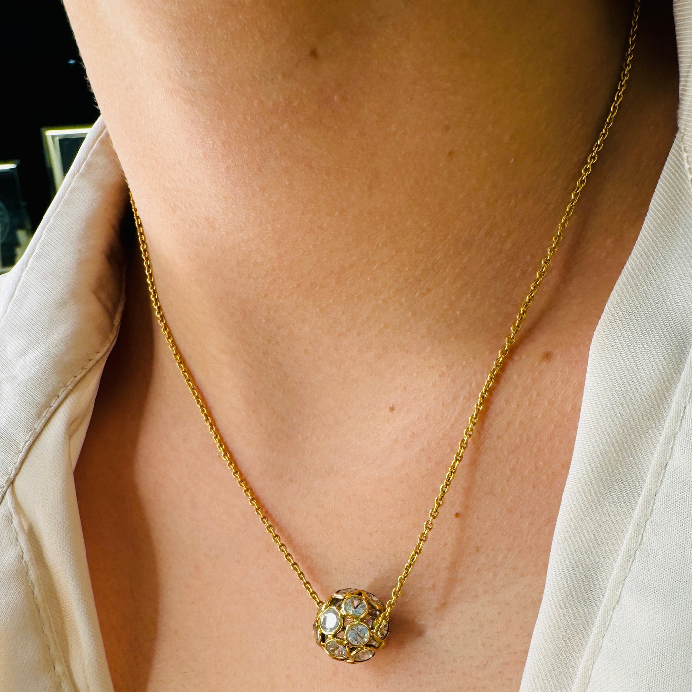 White Sapphire Necklace In 18K Yellow Gold - Tresor Collection Close-up of white sapphire pendant necklace on neckline – elegant minimalist jewelry style