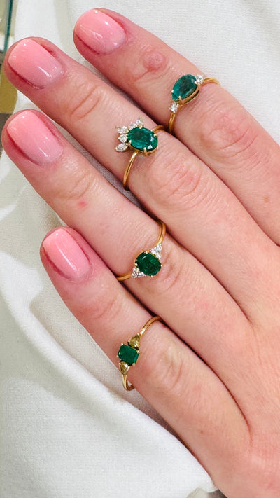 Emerald Oval & Diamond Ring In 18K Yellow Gold - Tresor Collection Emerald-cut emerald ring with pear-cut diamond accent worn on hand – delicate gold stacking ring Emerald and diamond gold ring on hand in natural light – elegant handcrafted ring
