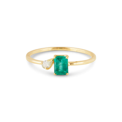 Emerald-cut emerald ring with pear-cut diamond accent in gold – minimalist fine-jewelry flatlay