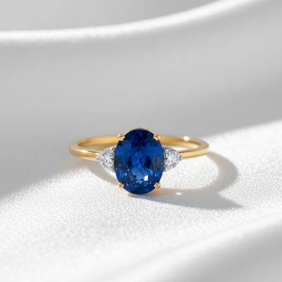 Gold ring with a blue gemstone on a white background 18K gold sapphire ring flatlay – luxury handcrafted fine jewelry by Tresor Collection