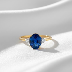 Gold ring with a blue gemstone on a white background