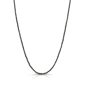 Close-up of 18k yellow gold necklace with 15.58 cts black diamond beads on white background. 18K gold black diamond bead necklace flatlay – luxury fine jewelry by Tresor Collection