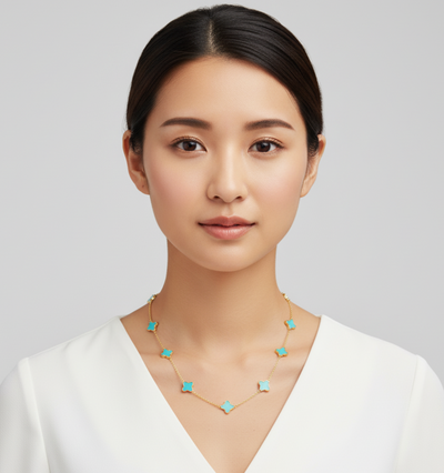 Woman wearing a gold necklace with turquoise stones against a plain background