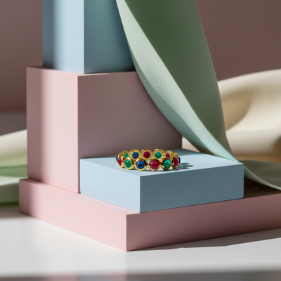 Colorful gemstone ring on a light blue box with a pink and green geometric background
