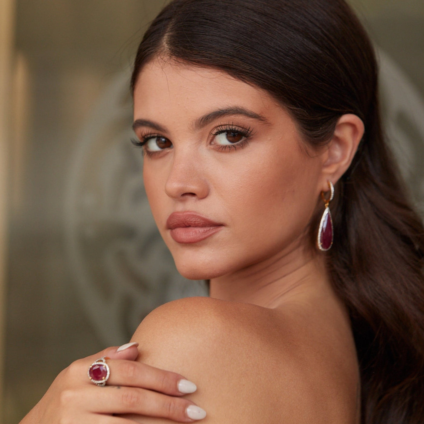 Angled view of model wearing ruby and diamond teardrop earrings in 18k yellow gold – Tresor Collection jewelry Close-up of pear-shaped cabochon ruby earrings in 18K gold – bespoke fine jewelry craftsmanship