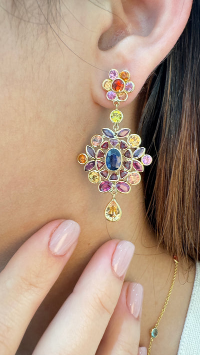 Close-up of a person wearing a colorful gemstone earring. Multi-sapphire drop earrings on model – handcrafted 18K gold fine jewelry for women by Tresor Collection