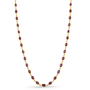 Gold necklace with red gemstones on a white background 18K gold rhodolite necklace flatlay – luxury fine jewelry by Tresor Collection