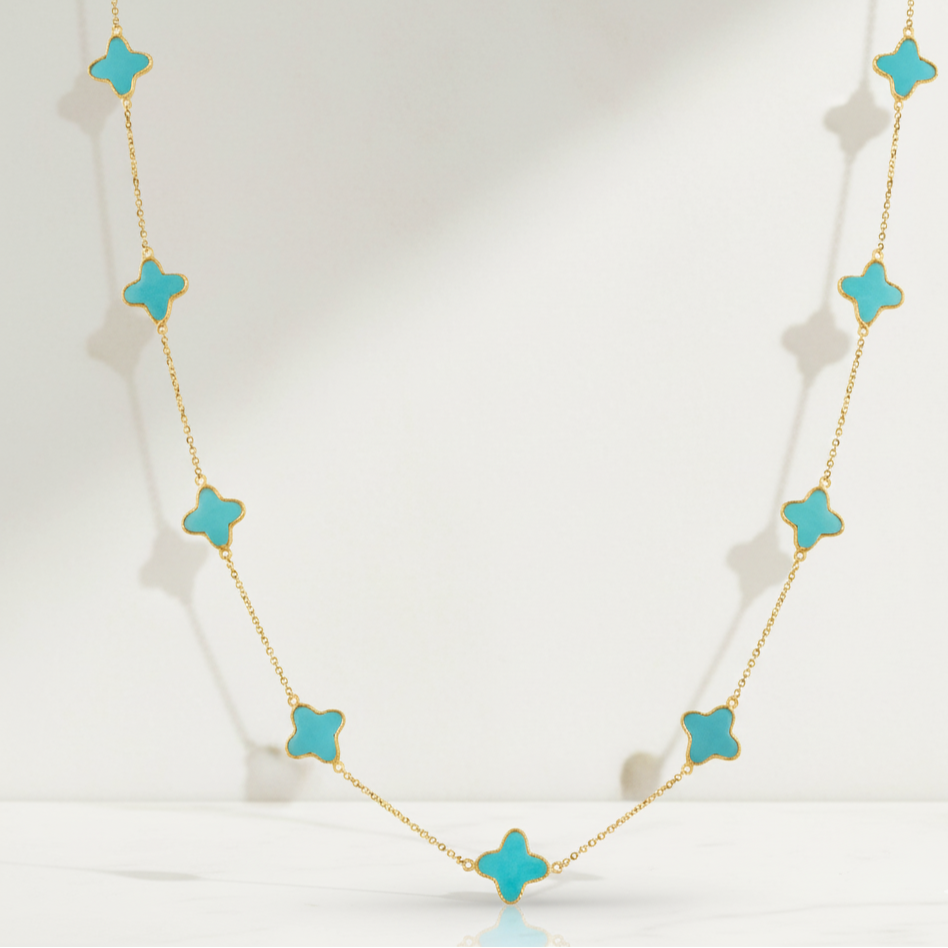 Necklace with turquoise star-shaped pendants on a white background Close-up of 18K gold turquoise star necklace – handcrafted fine jewelry from Tresor Collection boutique