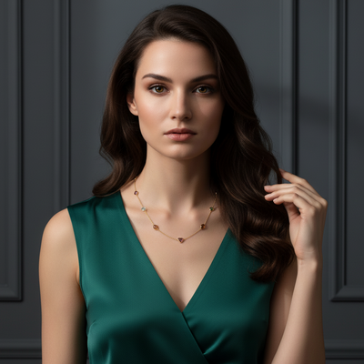Woman wearing a green dress with a dark background Fin Collection gold necklace styled for festive and gifting occasions – handcrafted gemstone jewelry by Tresor Collection