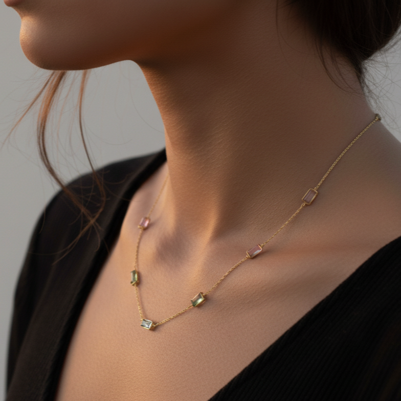 Necklace with small pendants on a person wearing a black top against a neutral background Elegant multicolor gemstone necklace on model – designer gold jewelry for women by Tresor Collection