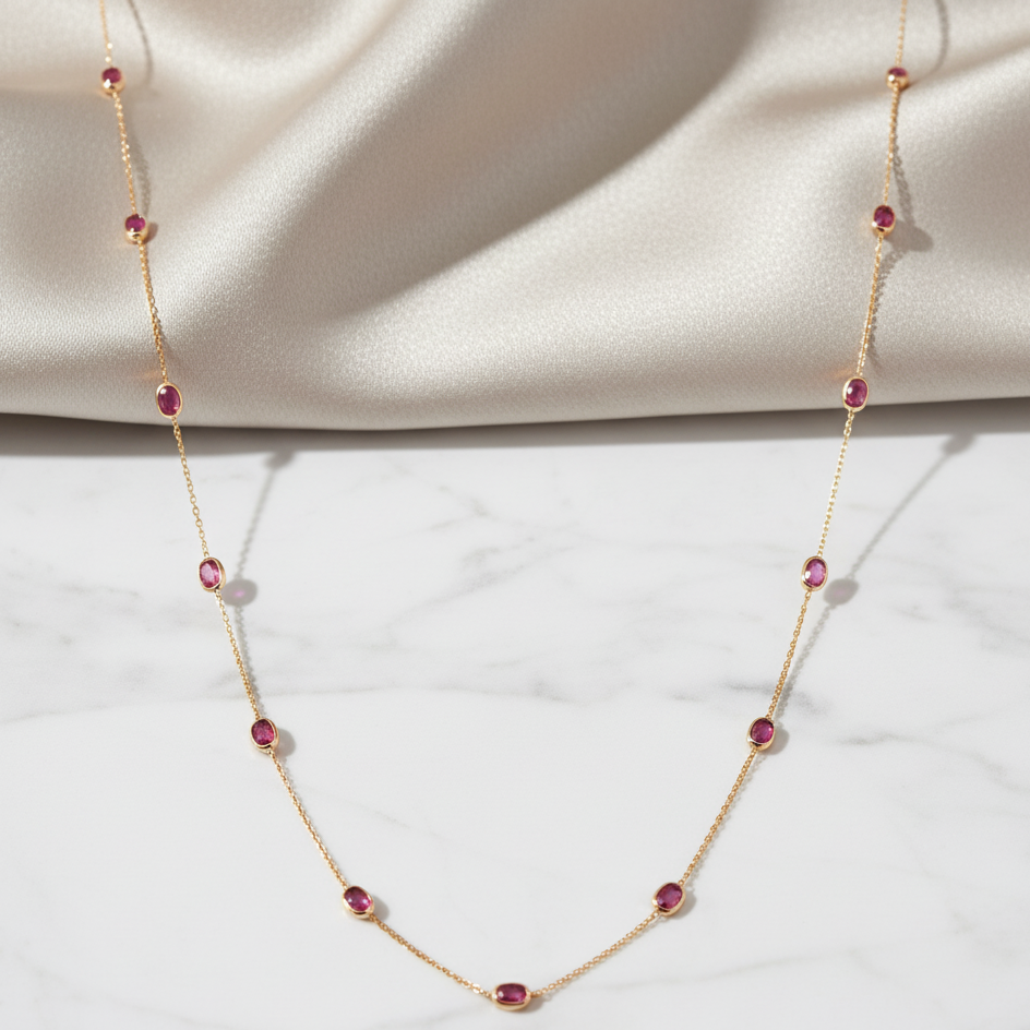 Gold necklace with red gemstones on a white background Close-up of 18K gold ruby necklace – handcrafted fine jewelry from Tresor Collection boutique