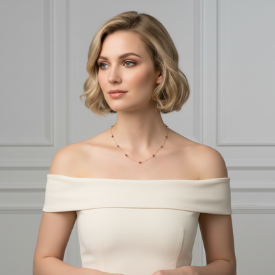Woman wearing an off-shoulder white dress against a gray paneled wall Ruby necklace styled for festive occasions – luxury handcrafted jewelry from Tresor Collection