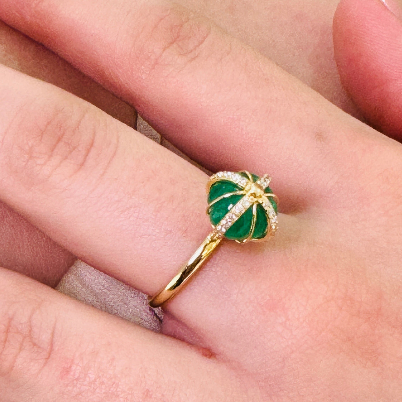 Gold ring with green gemstone on a finger Close-up of 18K gold emerald ring – designer handcrafted fine jewelry from Tresor Collection