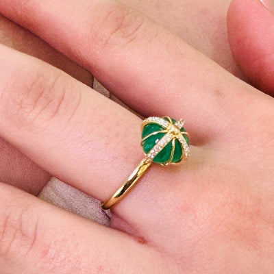 Gold ring with green gemstone on a finger Close-up of 18K gold emerald ring – designer handcrafted fine jewelry from Tresor Collection